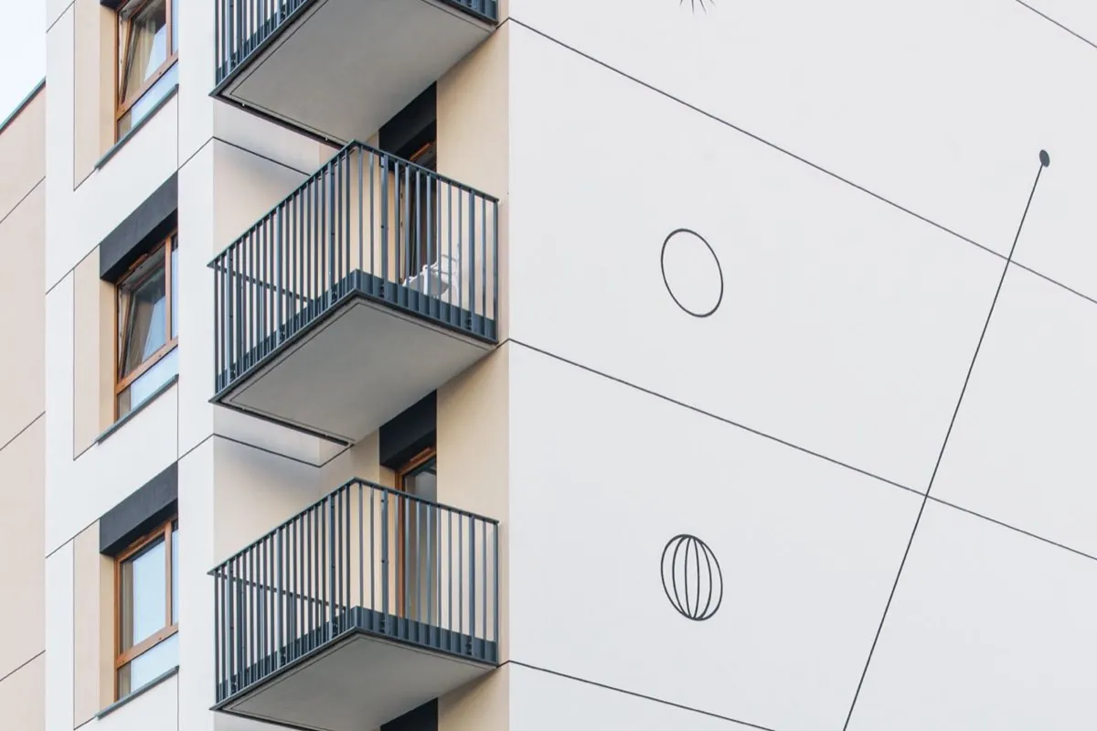 Part of the façade of the Harmonia Mokotów development in Warsaw with prefabricated balconies, shown alongside the design drawing